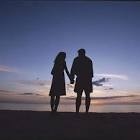 a couple holding hands at dusk / sunset on a beach